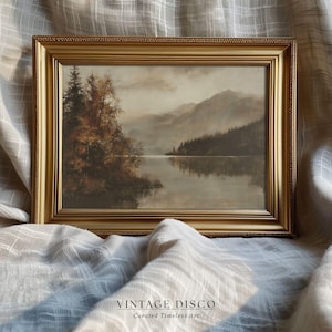 Puede incluir: Pintura de paisaje enmarcada en un marco dorado. La obra representa una serena escena lacustre con montañas y árboles. La pintura utiliza una paleta de colores apagados de marrones, verdes y grises. El texto "VINTAGE DISCO" está en la parte inferior. El marco mide unos 40 cm x 30 cm.