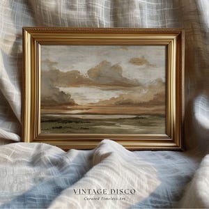 May include: A framed landscape painting in a gold-coloured ornate frame. The artwork shows a cloudy sky with shades of brown and grey, and a green and brown landscape. The text "VINTAGE DISCO Curated Timeless Art" is at the bottom.