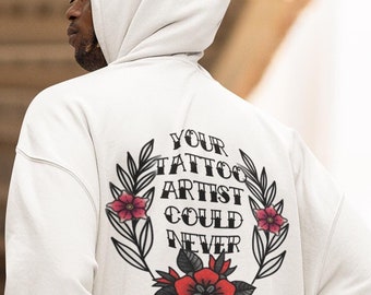 May include: White hooded sweatshirt with a floral design and the text "YOUR TATTOO ARTIST COULD NEVER" printed on the back.
