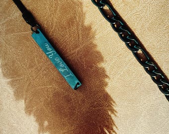 May include: A black chain necklace with a turquoise blue rectangular pendant that says "I love you" in white cursive writing.