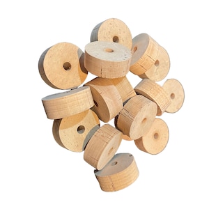 May include: A pile of natural cork rings with a hole in the center. The rings are light brown and have a rough texture.