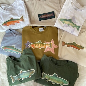 Peut inclure: Ensemble de trois tasses en céramique avec une finition mate et mouchetée. Les tasses sont dans des tons crème, gris clair et gris foncé. Chaque tasse a un design simple et minimaliste.