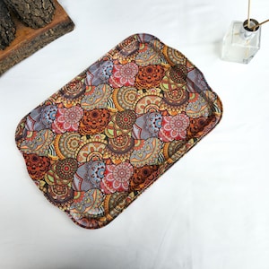 Op de afbeelding: Rechthoekig decoratief dienblad met een kleurrijk mandala-patroon in tinten rood, oranje, bruin en grijs. De lade heeft een geschulpte rand en staat tegen een witte achtergrond. Ideaal voor het serveren van eten of het uitstallen van items.
