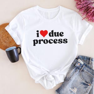 May include: White t-shirt with a red heart and the text "i ♥ due process" in black.