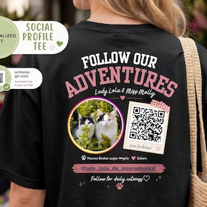 May include: A black t-shirt featuring a custom graphic on the back with the text FOLLOW OUR ADVENTURES, Lady Lola & Miss Molly, a circular photo of two cats, a scannable QR code, the handle @lady_lola_de_noorseboskat, and Follow for daily cuteness.