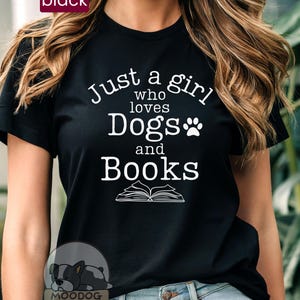 Può includere: Maglietta nera con testo bianco che recita "Just a girl who loves Dogs and Books" con un'impronta di zampa e un'immagine di un libro aperto.