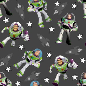 May include: A repeating pattern on a dark grey background featuring the character Buzz Lightyear in a white, green, and purple space suit with a clear helmet, interspersed with white five-pointed stars and dark grey rocket ship silhouettes.
