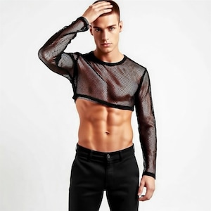 May include: Black mesh long-sleeve crop top. The top has a crew neck and a cropped hemline. The mesh fabric is see-through. The model is wearing black trousers. The background is white.