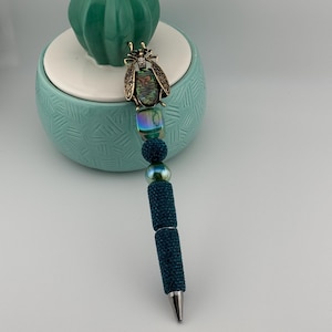 Prachtige groenblauwe kralenpen met prachtige insectentopper