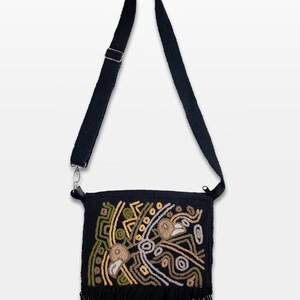 May include: Black crossbody bag with an embroidered design in shades of green, yellow, and beige. The bag features a long, adjustable strap and a fringe detail at the bottom. The bag is approximately 9 inches wide.