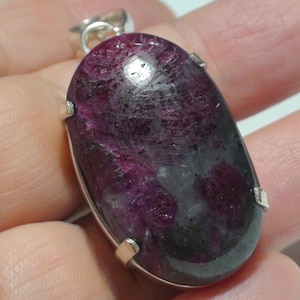 May include: A silver pendant featuring a large oval-shaped purple and grey gemstone. The gemstone has a distinctive, swirling pattern.
