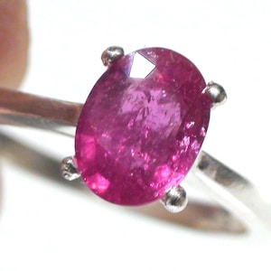 May include: A silver ring with a pink oval-shaped gemstone set in a prong setting.