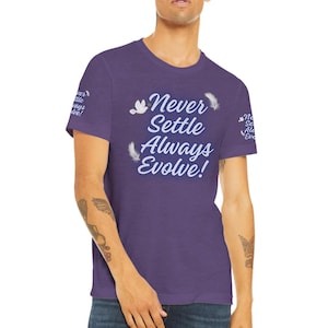Può includere: Maglietta viola con il testo "Never Settle Always Evolve!" in lettere bianche. La maglietta ha un aspetto vissuto e presenta grafiche di piume bianche.