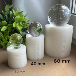May include: Three white cylindrical silicone moulds with the brand name LOFIORE embossed on the side. Each mould is topped with a clear glass sphere. The moulds are labelled with sizes 30 mm, 40 mm, and 60 mm, indicating their respective diameters.