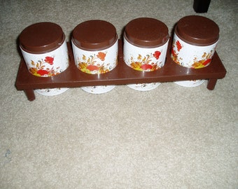 Four Small Metal Canisters With Plastic Lids