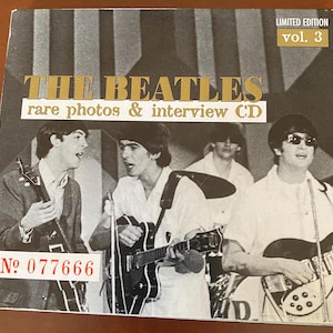 May include: A black and white CD cover featuring The Beatles with the text "THE BEATLES" in gold letters. The cover also includes the text "rare photos & interview CD" and "LIMITED EDITION vol. 3". A sticker with the number "No 077666" is on the bottom left.