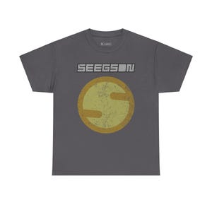 Può includere: Una t-shirt grigio scuro con un logo in stile vintage che presenta la parola "SEEGSON" in lettere bianche e un cerchio giallo con una "S" stilizzata al suo interno.