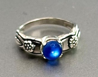 May include: A silver ring featuring a blue gemstone and floral accents.