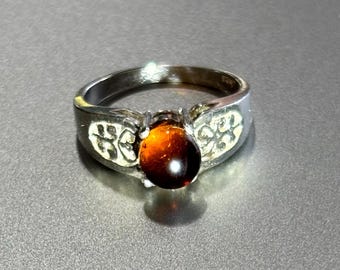 May include: A silver ring with a brown oval-shaped gemstone set in a decorative setting.