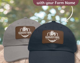 May include: Two baseball caps with a brown leather patch featuring a tractor and the text "Marigold Farms". One cap is gray and the other is navy blue.