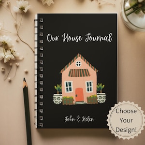 May include: A black spiral bound journal with a pink house illustration and the text "Our House Journal" and "John & Helen".