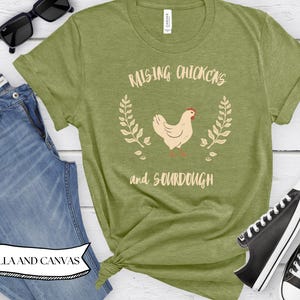 May include: Green t-shirt with the text "Raising Chickens and Sourdough" and a graphic of a chicken with a wreath design.
