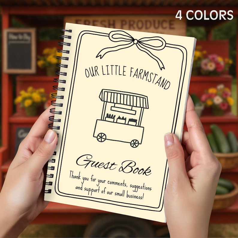 May include: A spiral-bound guest book with a cream-colored cover is held in front of a red produce stand. The cover features a black line drawing of a farm stand, a bow, and the words "OUR LITTLE FARMSTAND" and "Guest Book". The text reads "Thank you for your comments, suggestions and support of our small business!"