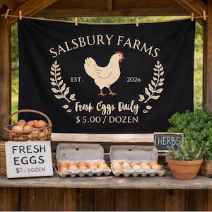 May include: A black banner with the text "Salsbury Farms" and a hen illustration. Below the banner, a wooden table displays fresh eggs in cartons and a basket. A sign reads "Fresh Eggs £5/dozen". Herbs in a terracotta pot are also visible.