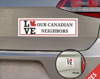 Könnte beinhalten: Ein weißer Stoßfängeraufkleber mit rotem und schwarzem Text, der "Love Our Canadian Neighbors" mit einem roten Ahornblatt lautet. Der Aufkleber befindet sich auf einem silbernen Auto.