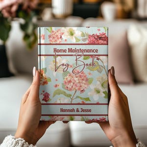 May include: A floral-patterned "Home Maintenance Log Book" with a light blue background and pink and white flowers. The book has the names "Hannah & Jesse" printed on the bottom.