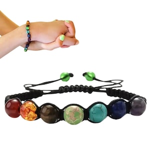 May include: A black cord bracelet with seven round gemstone beads in the colors of the rainbow. The beads are red, orange, yellow, green, blue, indigo, and violet.