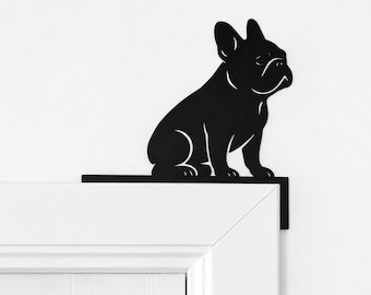 Puede incluir: Una silueta de metal negro de un Bulldog Francés sentado, diseñada para montarse en la esquina del marco de una puerta. El recorte presenta líneas limpias que definen las orejas, los rasgos faciales y la postura del perro en un perfil plano.