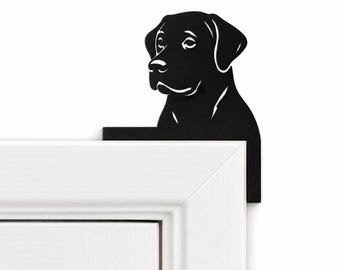 Puede incluir: Un adorno de metal negro para puerta con la silueta de la cabeza y los hombros de un perro Labrador. El perro se muestra de perfil, mirando hacia la izquierda, con detalles recortados que definen los ojos, la nariz y el hocico.