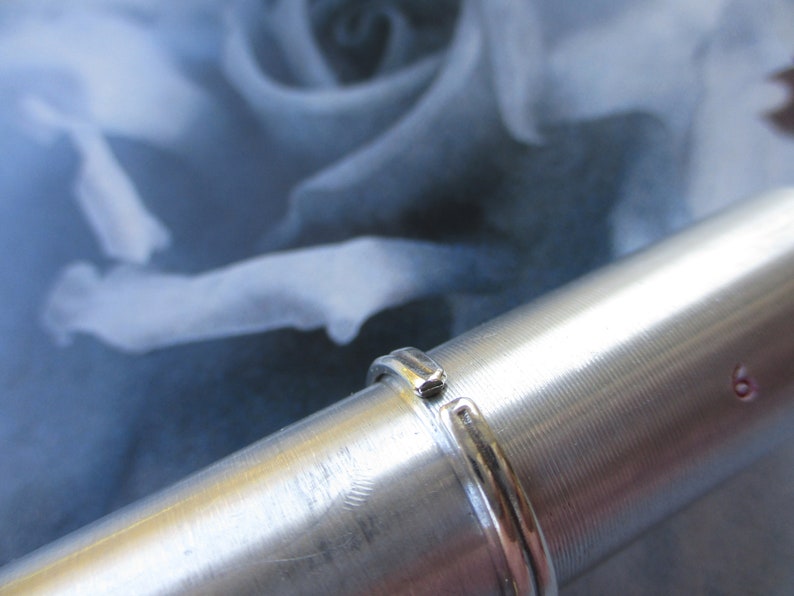 May include: A silver ring with a smooth, polished finish. The ring is on a silver cylinder.