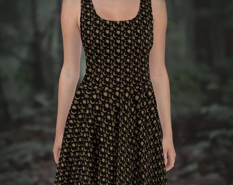 May include: Black skater dress with a gold celestial pattern of moons, stars, and other shapes. The sleeveless dress has a scoop neckline and a flared skirt, perfect for casual wear or a night out.