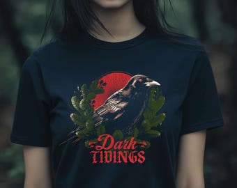 May include: Navy blue t-shirt featuring a detailed illustration of a raven with red eyes, set against a red sunburst and green foliage. The words "Dark Tidings" are written in red script below the raven.