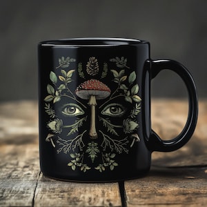 May include: Black ceramic mug with a forest-themed design. The design features a mushroom, eyes, and various plants on a black background.