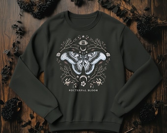 May include: Dark green sweatshirt featuring a detailed moth and botanical design. The graphic includes a moth with intricate wing patterns, an eye, crescent moon, and the text "NOCTURNAL BLOOM". The design is surrounded by branches and floral elements.