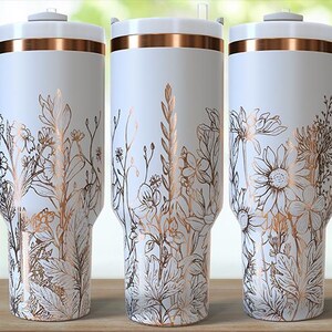 May include: White travel mugs with a floral design in gold and brown tones. Each mug has a handle and a lid with a gold band. The mugs are decorated with various flowers and foliage. The logo "UNQUELY SAMI" is on the left mug.