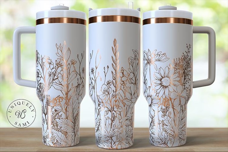 May include: White travel mugs with a floral design in gold and brown tones. Each mug has a handle and a lid with a gold band. The mugs are decorated with various flowers and foliage. The logo "UNQUELY SAMI" is on the left mug.