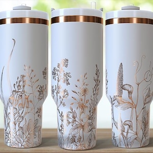 May include: Three white travel mugs with copper-colored accents and handles. Each mug features a floral design in shades of copper and brown. The mugs have a lid and a handle. The logo "Uniquely Sami" is visible on the left mug.