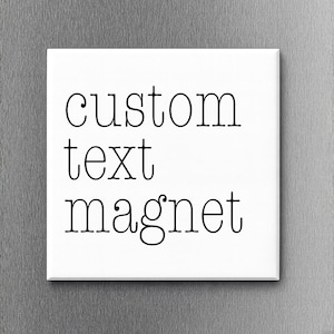 May include: A square white magnet featuring the black text custom text magnet in a clean, sans-serif font. The magnet has a smooth, flat surface and is positioned against a brushed metallic background, displaying clear, legible lettering.