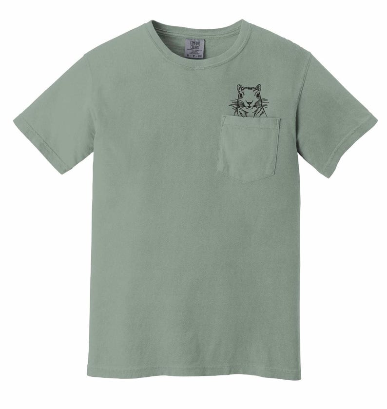 A light green t-shirt with a small black illustration of a squirrel peeking out of a pocket on the front.