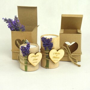 May include: Two small wooden candle holders with lavender sprigs and personalized heart-shaped wooden tags. The tags read "Alexander & Sylvie" and "Amelia & Thomas". The candle holders are packaged in brown cardboard boxes with heart-shaped cutouts.
