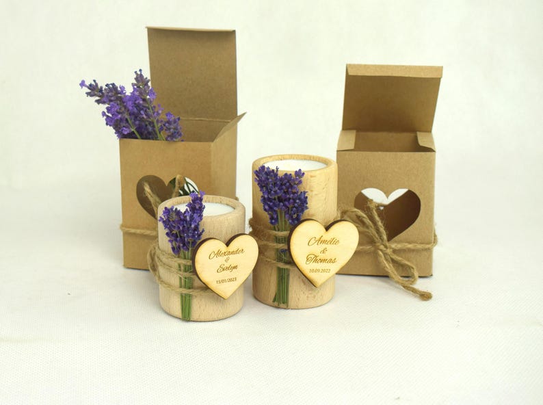 May include: Two small wooden candle holders with lavender sprigs and personalized heart-shaped wooden tags. The tags read "Alexander & Sylvie" and "Amelia & Thomas". The candle holders are packaged in brown cardboard boxes with heart-shaped cutouts.