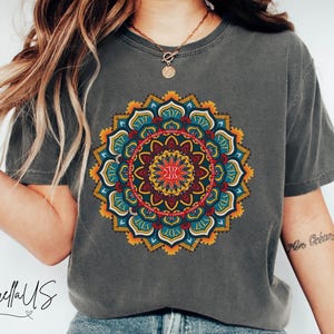 May include: A charcoal grey t-shirt with a colorful mandala design. The mandala is a circular pattern with intricate details in shades of blue, red, yellow, and orange.