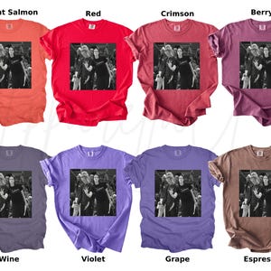May include: A collection of eight different colored t-shirts. Each shirt features a black and white image of people. The shirts are in various colors, including bright salmon, red, crimson, berry, wine, violet, grape, and espresso.