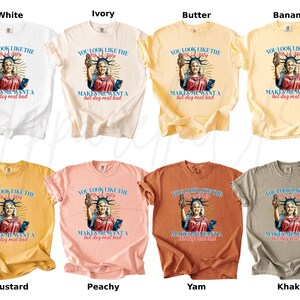 Puede incluir: Una colecci&oacute;n de camisetas en varios colores, incluyendo blanco, marfil, mantequilla, pl&aacute;tano, mostaza, melocot&oacute;n, &ntilde;ame y caqui. Cada camiseta presenta un gr&aacute;fico de la Estatua de la Libertad con el texto: "You look like the 4th of July makes me want a hot dog real bad."