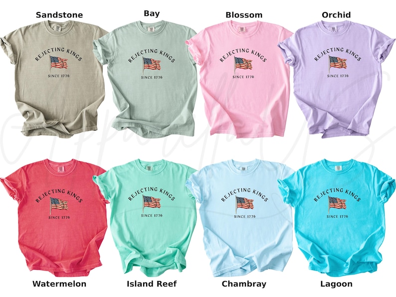 May include: A collection of eight short-sleeved t-shirts in various colors, including beige, green, pink, purple, red, teal, light blue, and turquoise. Each shirt features the text "Rejecting Kings Since 1776" with an American flag graphic.