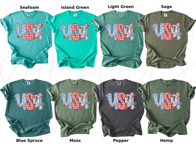 May include: A collection of eight t-shirts in various colors, each featuring the word "USA" in a patriotic design. The letters are a mix of blue polka dots and red gingham patterns. The shirts are in shades of green, blue, and gray.